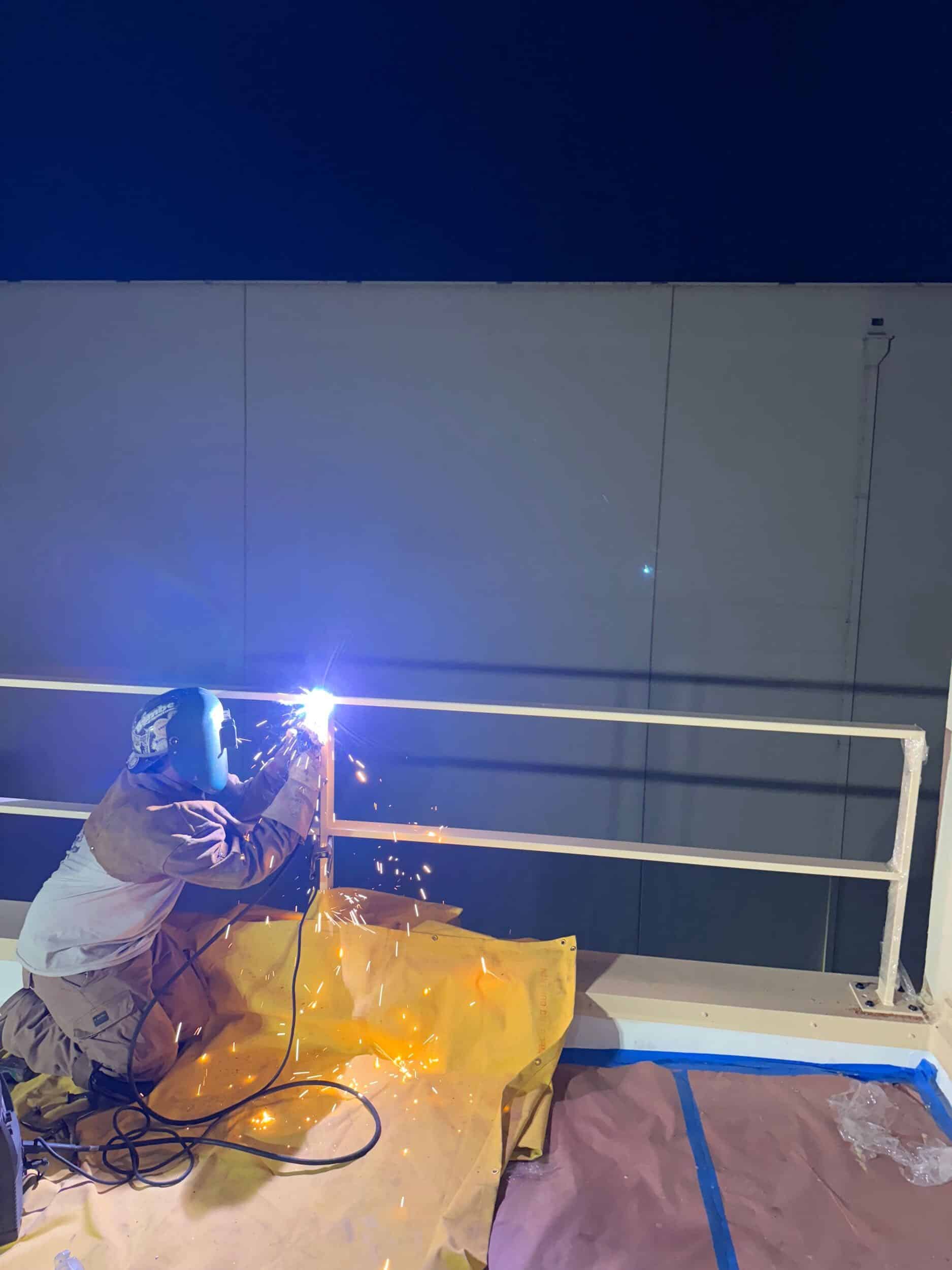 Welder installing a permanent roof guardrail
